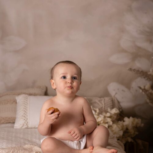 Bébé en couche mange des petits gâteaux dans un décor chic bohème en studio, séance photographie enfant à Giberville