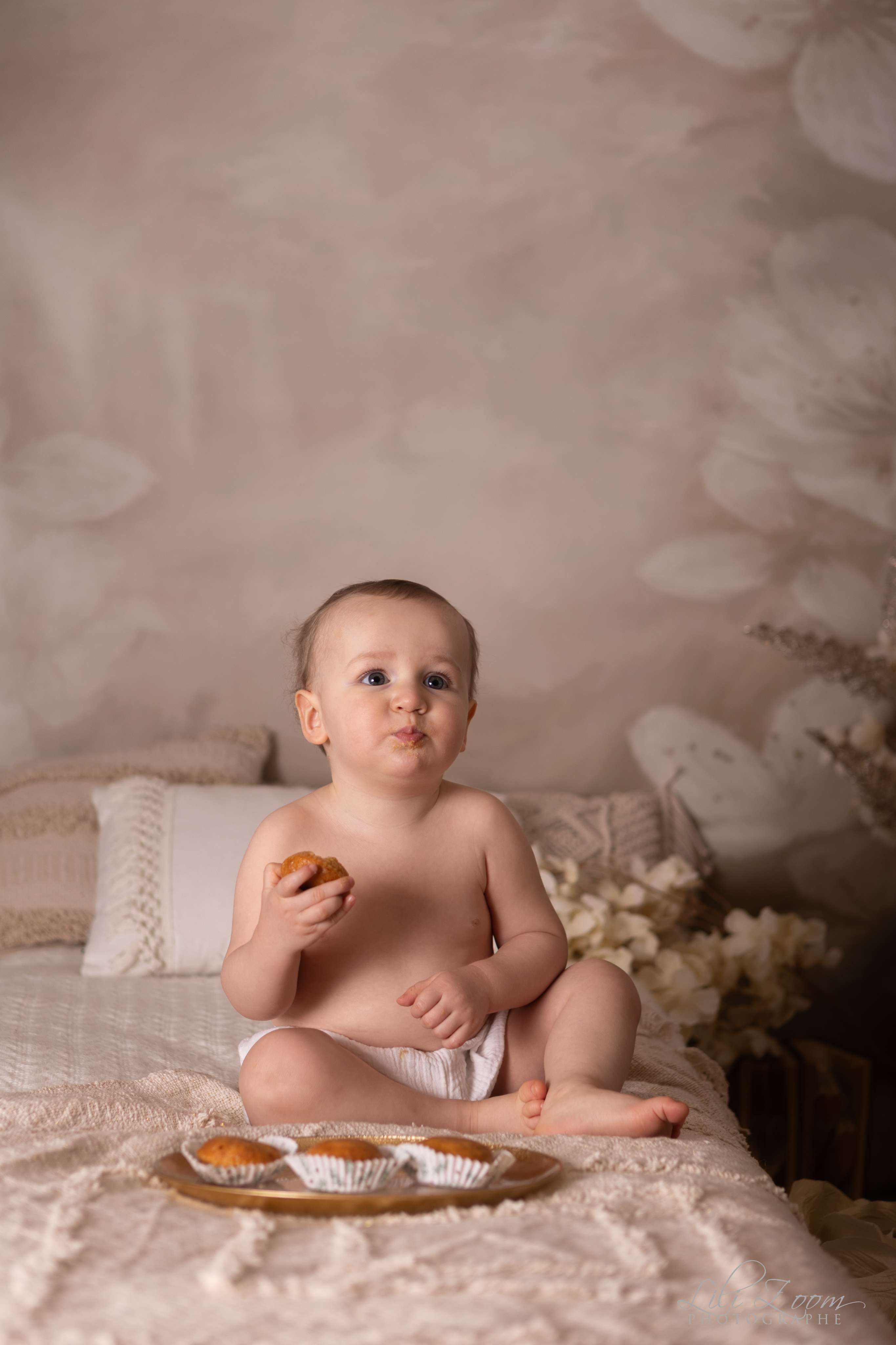 Bébé en couche mange des petits gâteaux dans un décor chic bohème en studio, séance photographie enfant à Giberville