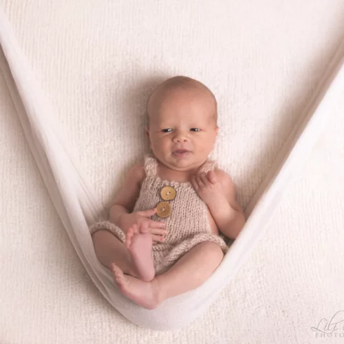 Nouveau-né éveillé installé confortablement dans un hamac en coton blanc - Photographe Naissance à Giberville