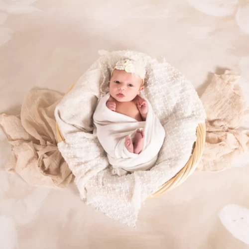 Nouveau-né éveillé et emmailloté dans un cocon de douceur blanc au cœur d'un panier en osier - Photographe Naissance proche de Mondeville