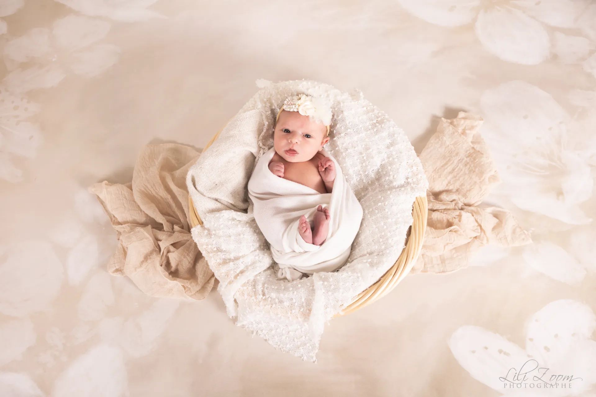 Nouveau-né éveillé et emmailloté dans un cocon de douceur blanc au cœur d'un panier en osier - Photographe Naissance proche de Mondeville