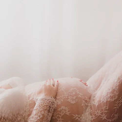 Séance tout en douceur pour une futur maman qui pose ses mains sur son ventre arrondi, séance grossesse au studio photo de Giberville