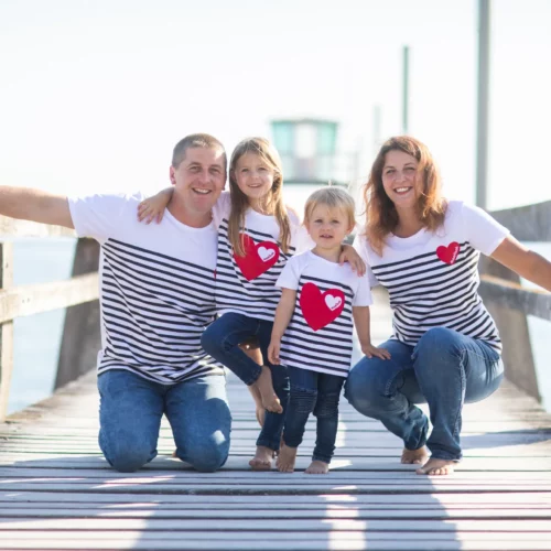 Famille complice en marinières souriant sur un ponton en bois face à la mer - Photographe Famille à Luc-sur-Mer