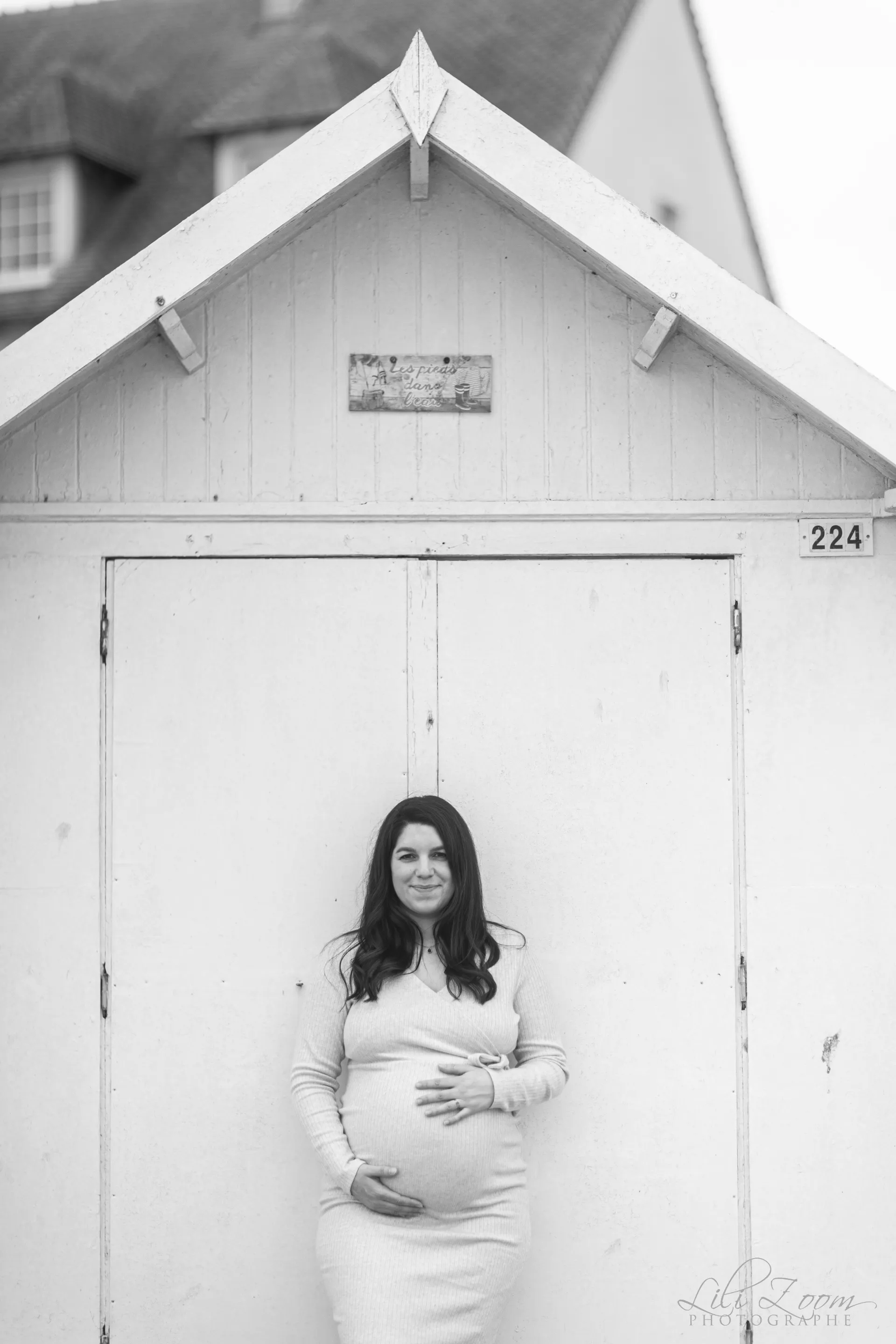 Une femme enceinte se repose sur une cabine de plage de la côté normande, shooting grossesse professionnel en extérieur à Luc sur Mer