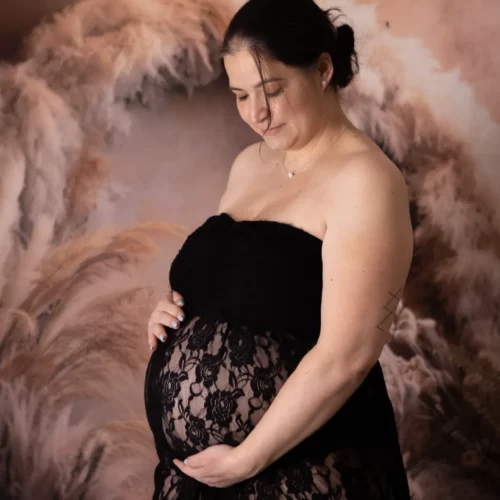 Une femme enceinte porte une tenue fine dans un décor de plumes et de fleurs de pampa, séance photo grossesse en Normandie