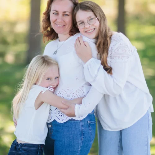 Une maman et ses feux filles se font un câlin dans la forêt aux couleurs d'été, séance famille extérieure à Caen