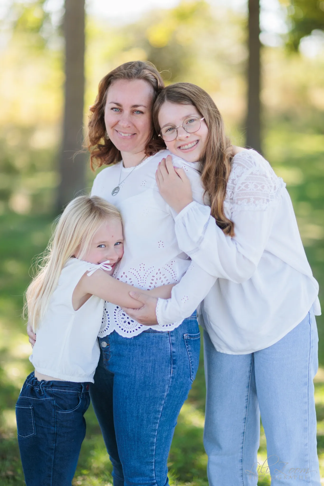 Une maman et ses feux filles se font un câlin dans la forêt aux couleurs d'été, séance famille extérieure à Caen