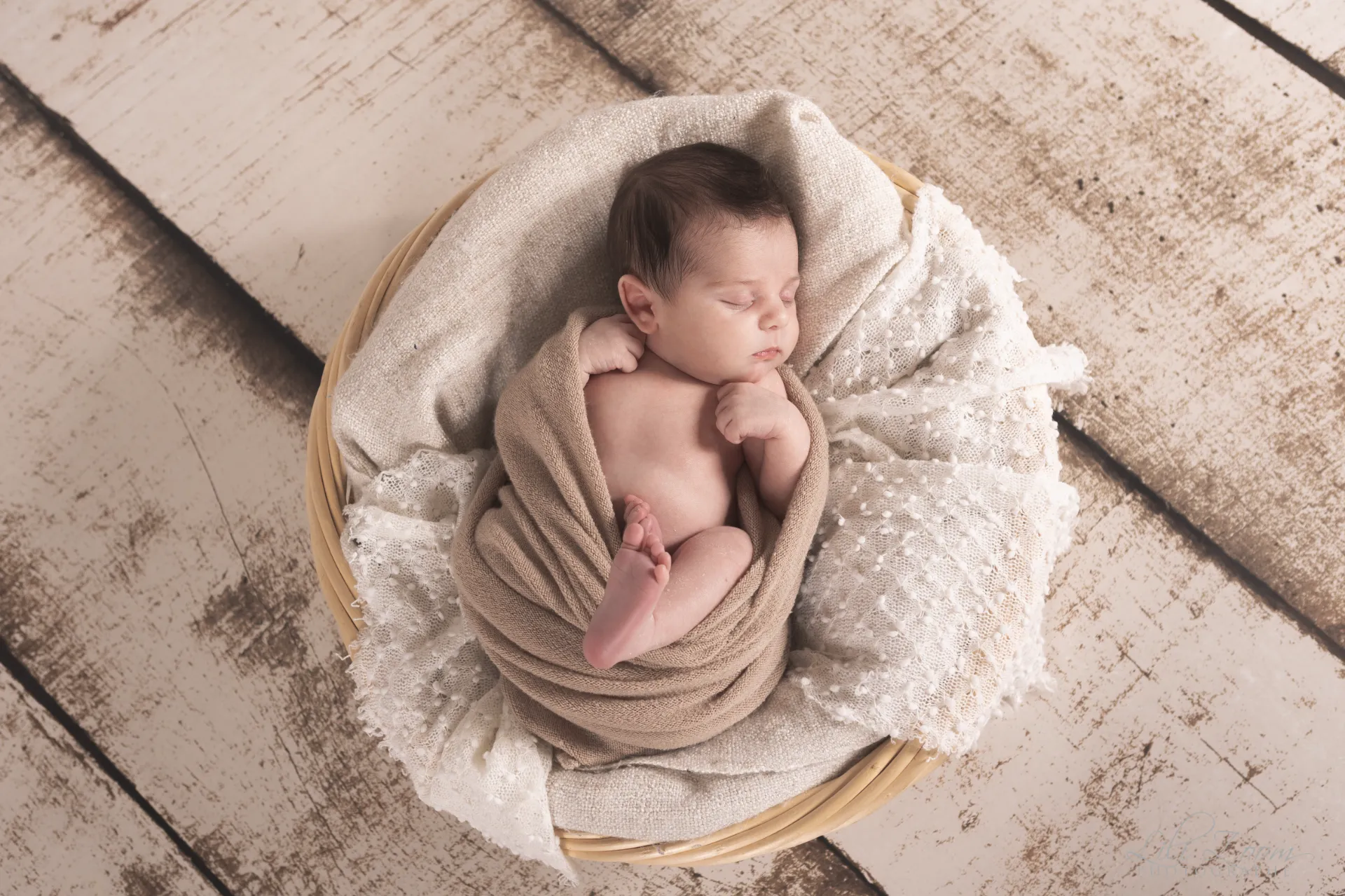 Nouveau-né endormi paisiblement dans un panier en osier avec des couvertures douces et dentelle - Photographe Naissance proche de Colombelles