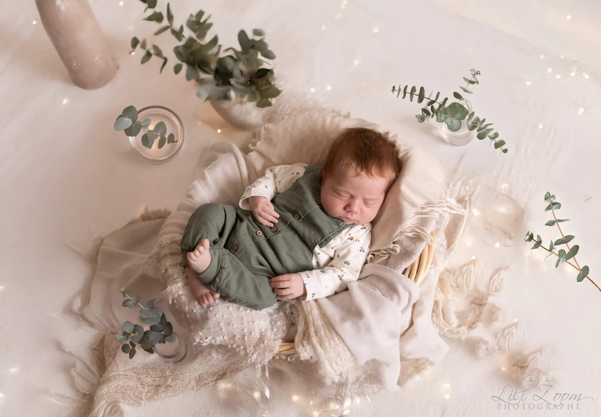 Nouveau-né paisible endormi dans un petit panier entouré d'eucalyptus et de douces lumières scintillantes - Photographe Naissance proche de Colombelles
