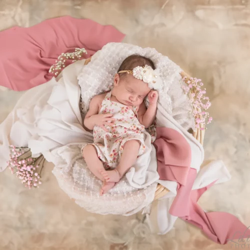 Nouveau-né paisiblement endormi dans un panier fleuri aux teintes douces et printanières - Photographe Naissance à Giberville