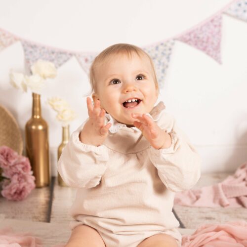 Un bébé pose au studio en petite tenue, il sourie et rigole pour la photographie en Normandie