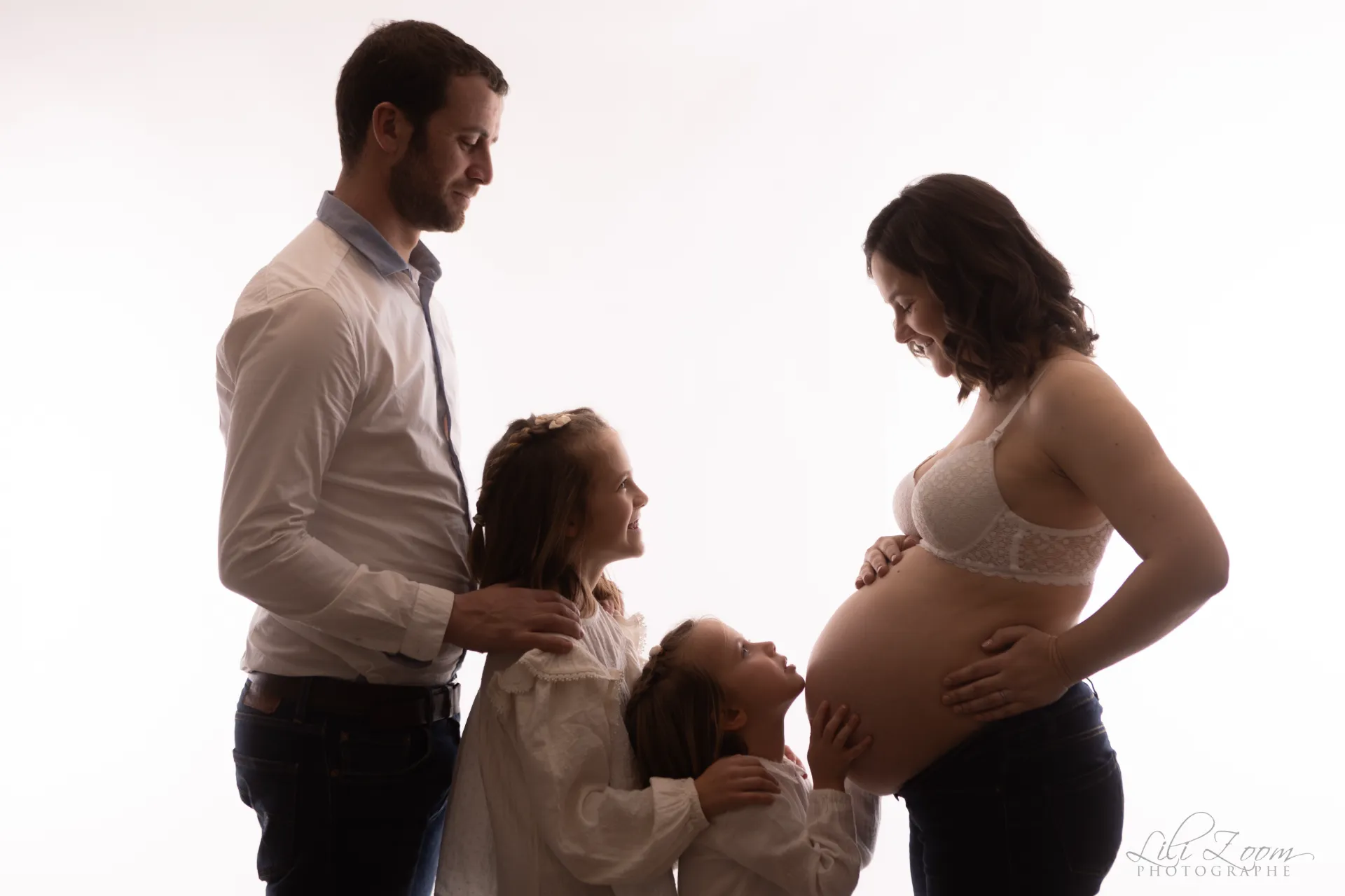 Séance grossesse en famille, le papa et ses enfants regardent la future maman dans les yeux, shooting professionnel maternité en Normandie