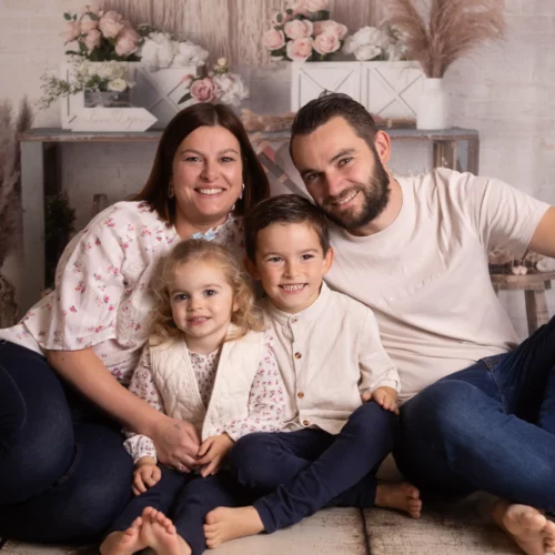 Portrait de famille complice et souriante dans un décor studio bohème et fleuri - Photographe Famille proche de Cuverville