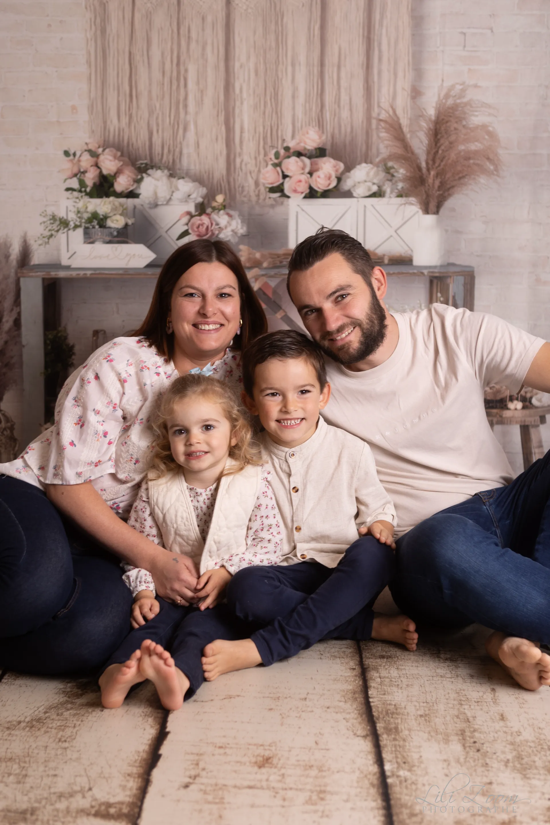 Portrait de famille complice et souriante dans un décor studio bohème et fleuri - Photographe Famille proche de Cuverville