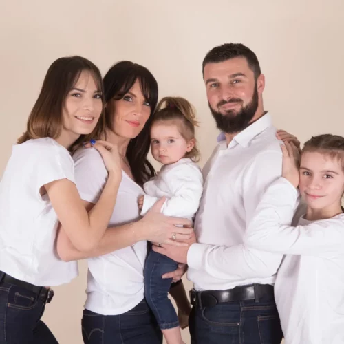 Une famille nombreuse s'enlace sur un fond couleur nature en studio photographique, photographe de portrait de famille en Normandie