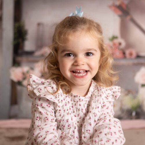 Une fillette aux cheveux bouclés avec des roses et des coeurs, séance photo famille enfant à Cuverville