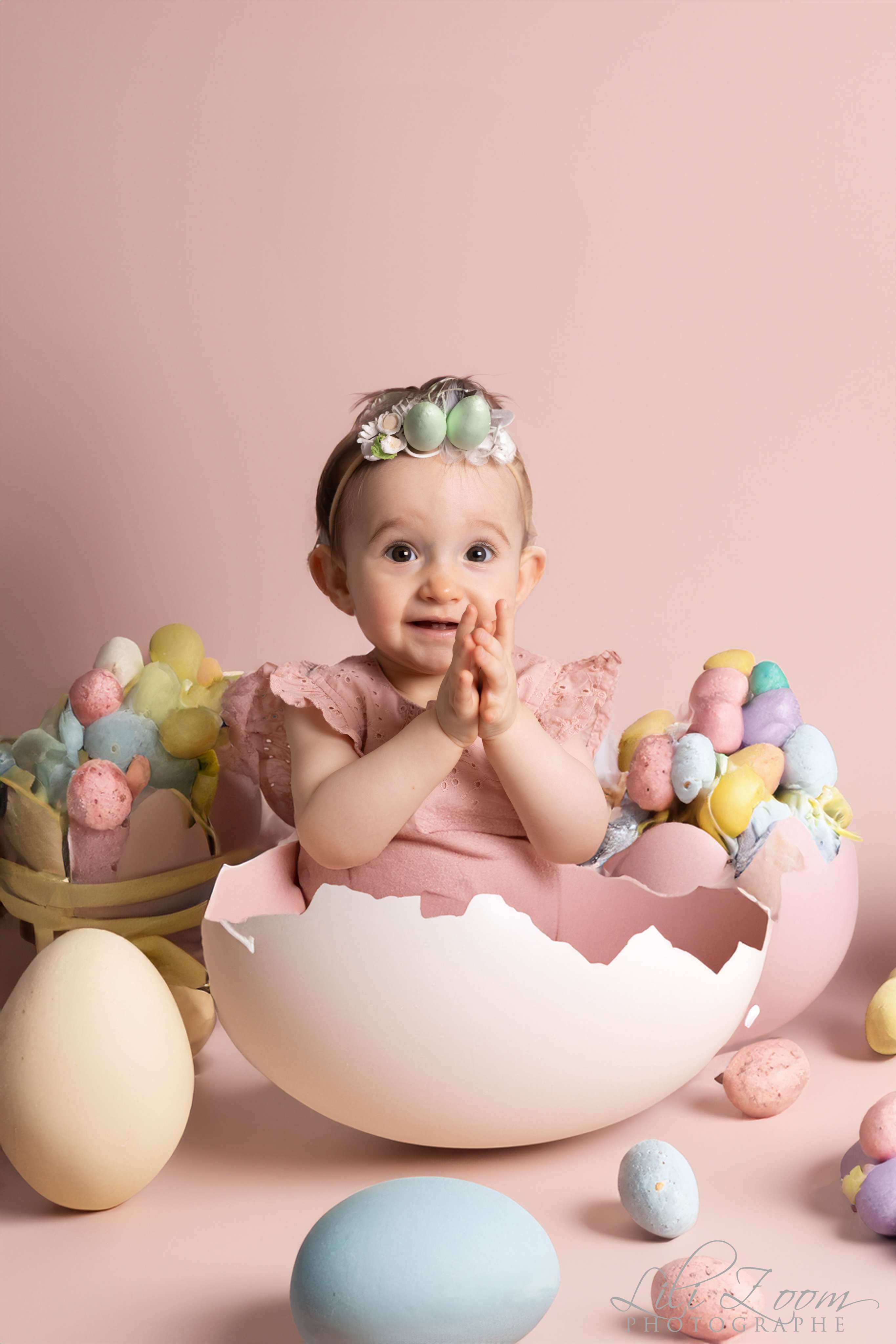 Un bébé avec un ruban dans un oeuf géant avec une décoration de Pâques, séance photo à thème sur Démouville