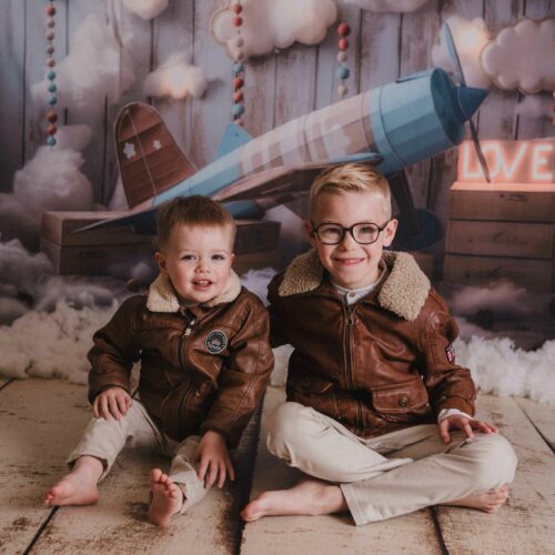 Deux frères en blousons d'aviateur devant un avion et des nuages, séance photo à thème en studio à Caen