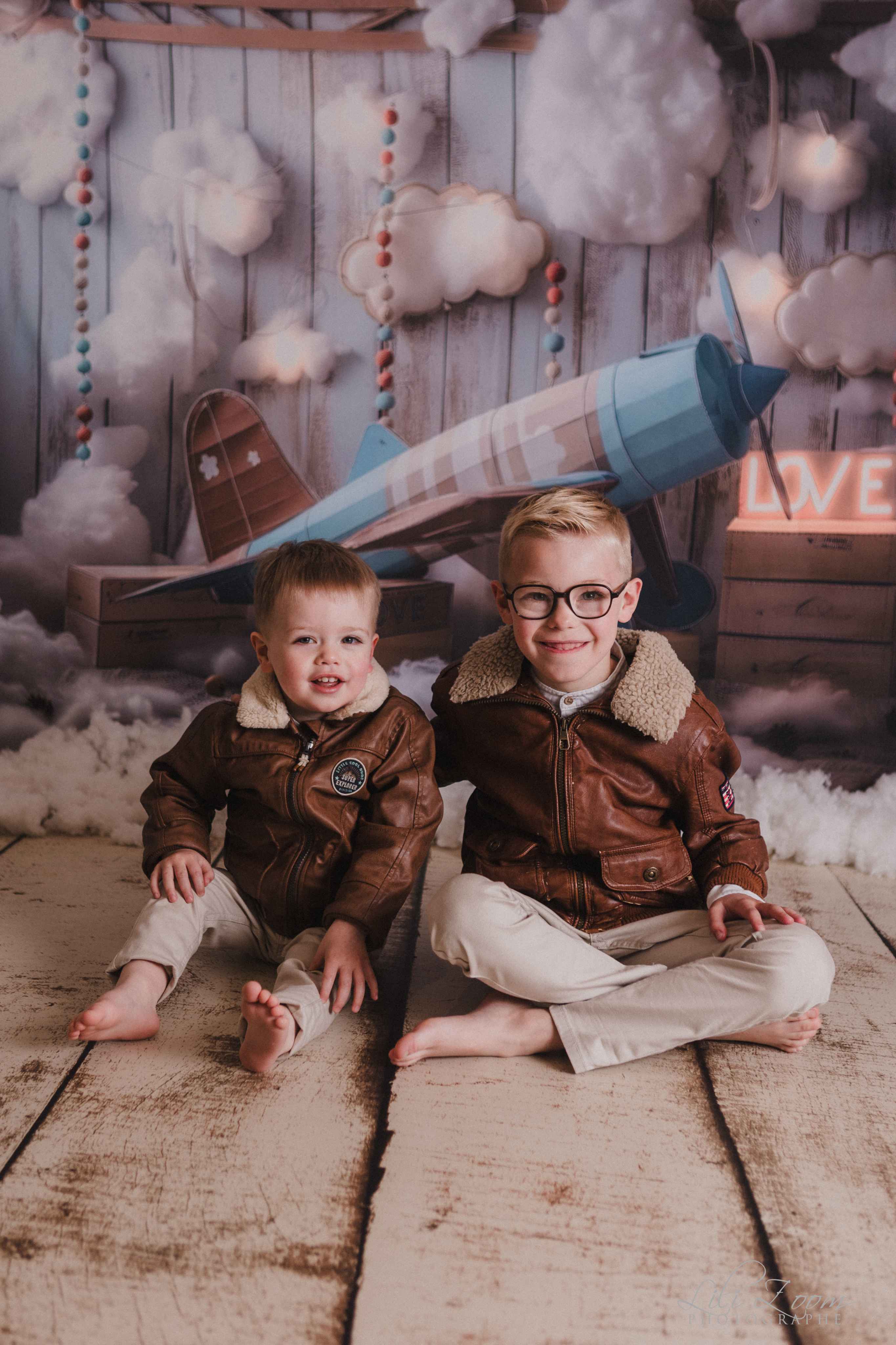 Deux frères en blousons d'aviateur devant un avion et des nuages, séance photo à thème en studio à Caen