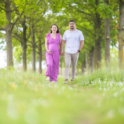 Un couple avec une femme enceinte marche main dans la main dans la forêt, séance grossesse nature à Colombelles