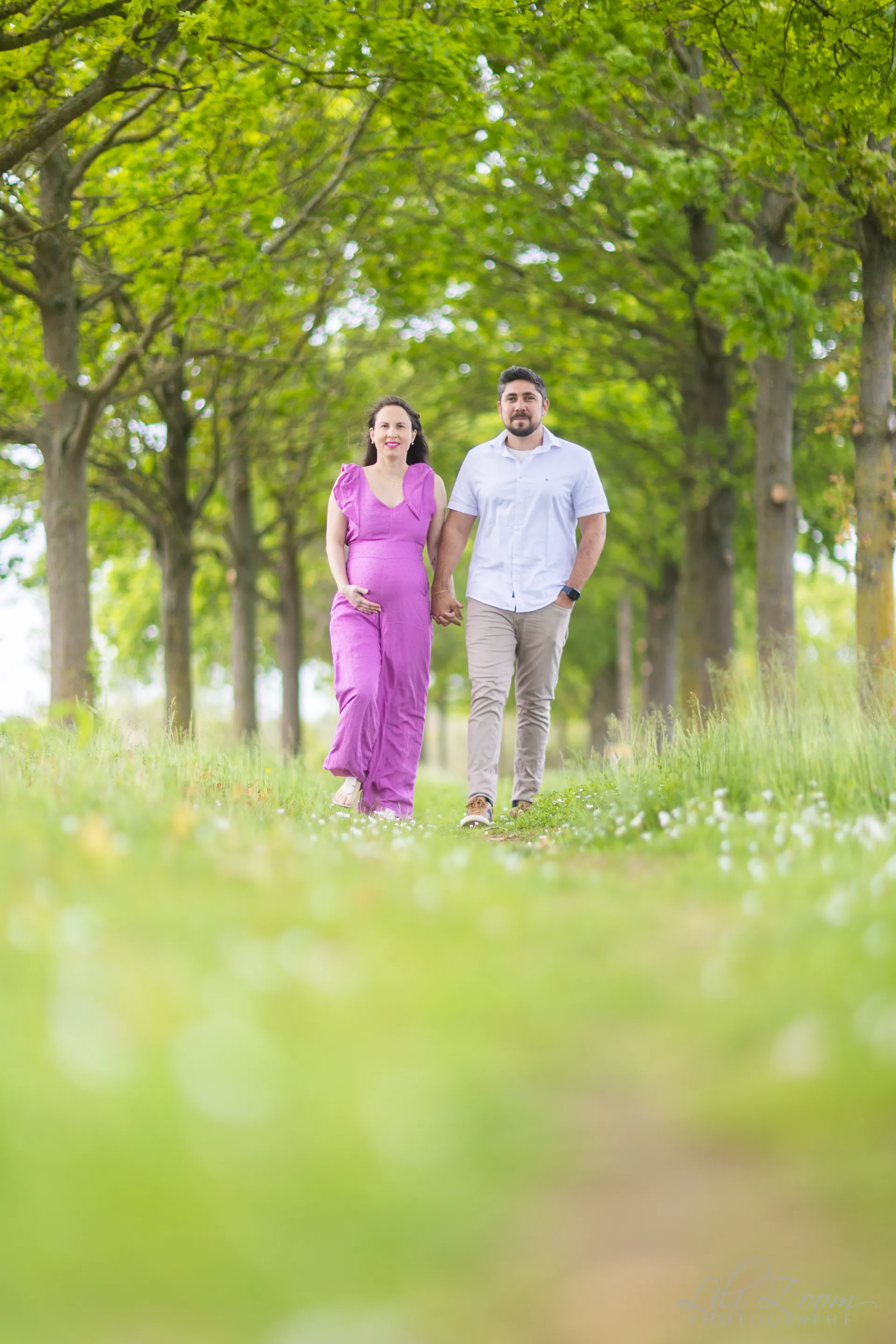 Un couple avec une femme enceinte marche main dans la main dans la forêt, séance grossesse nature à Colombelles