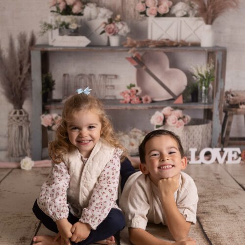 Une petite fille et un petit garçon sourient dans un décor romantique, lumière douce et naturelle, séance photo famille à Giberville