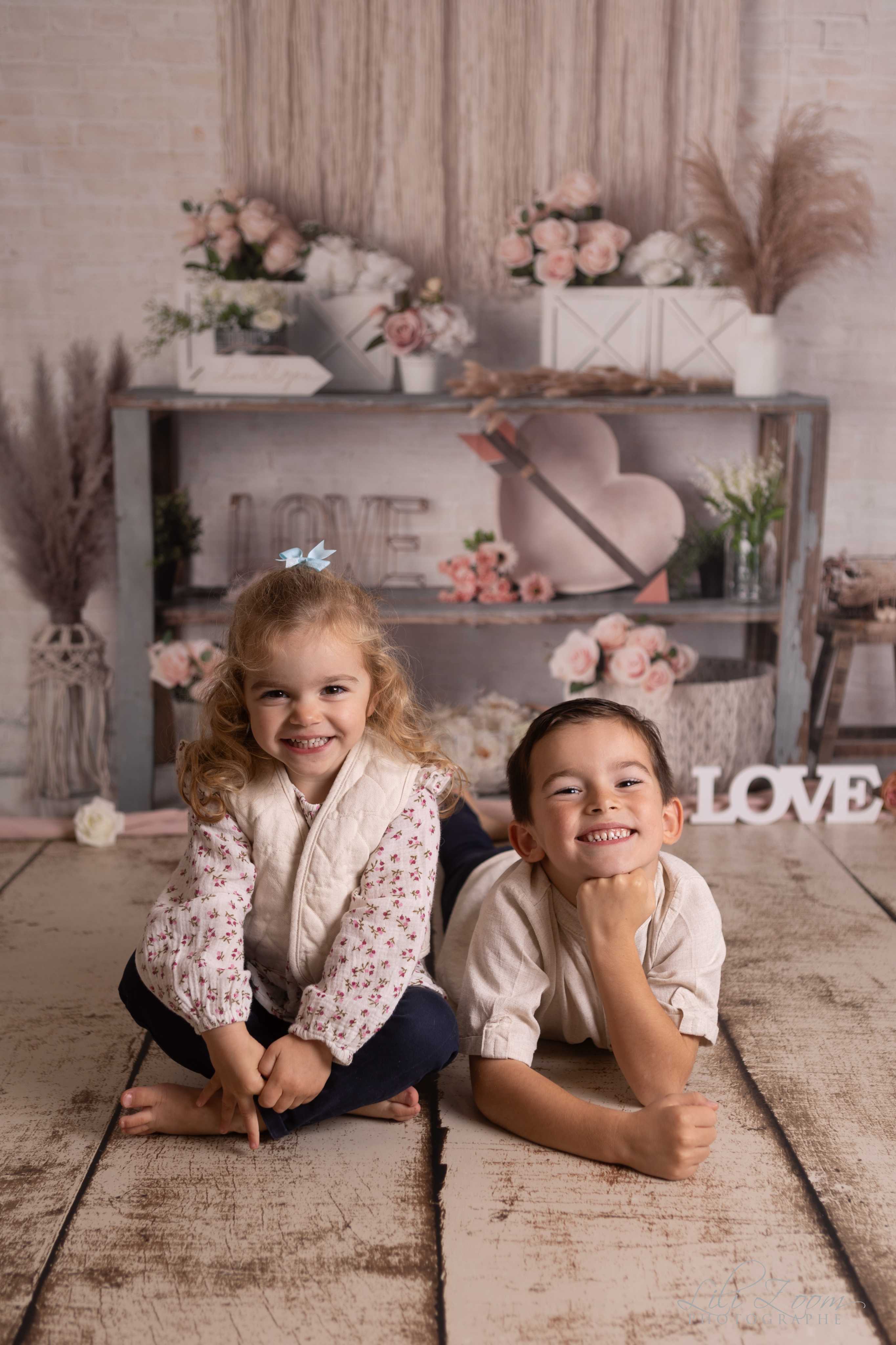 Une petite fille et un petit garçon sourient dans un décor romantique, lumière douce et naturelle, séance photo famille à Giberville