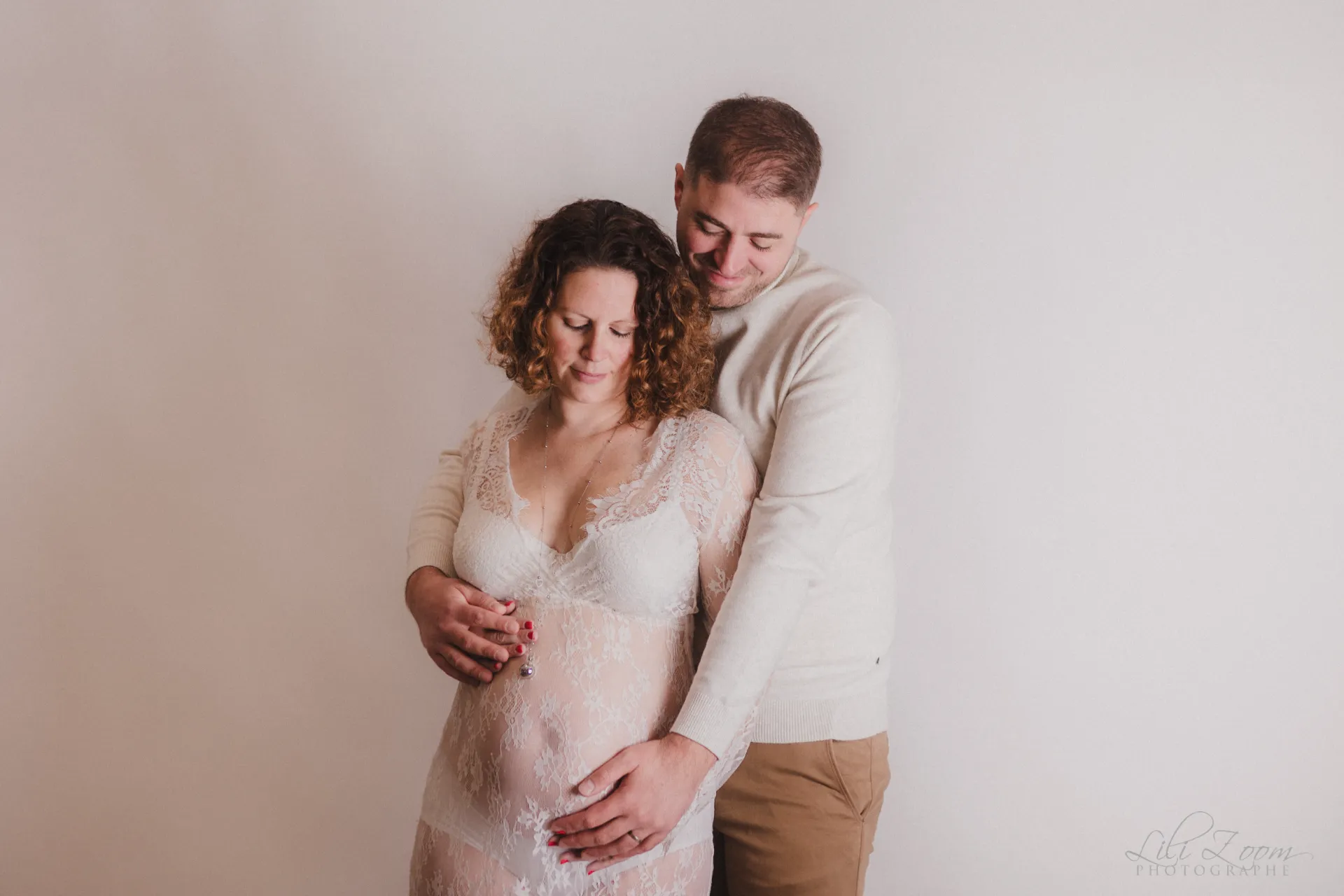 Un couple se câline en attendant bébé, le père caresse le ventre enceinte de la future maman, séance douceur grossesse en Normandie