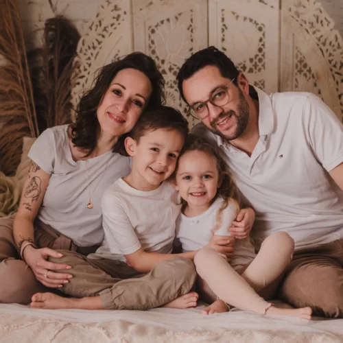 Portrait de famille complice et souriante dans un décor studio bohème aux tons naturels et chaleureux - Photographe Famille à Giberville