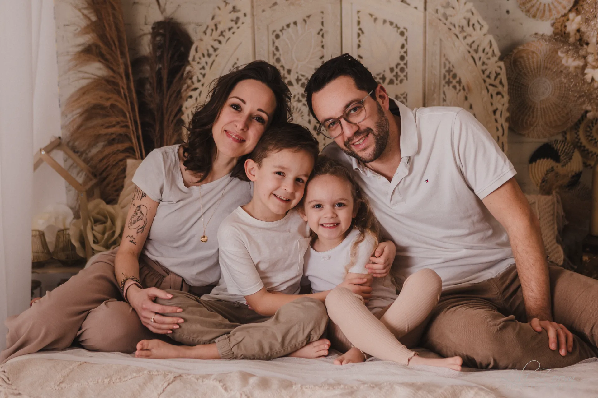 Portrait de famille complice et souriante dans un décor studio bohème aux tons naturels et chaleureux - Photographe Famille à Giberville