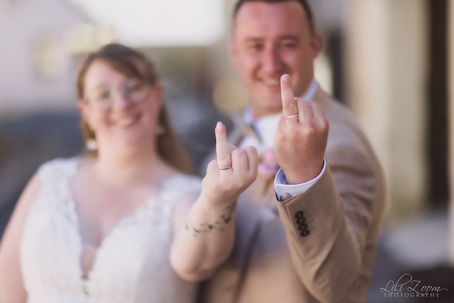 Couple de mariés complices et rock'n'roll montrant leurs alliances avec humour lors d'une séance décalée - Photographe Famille au Centre-ville de Caen