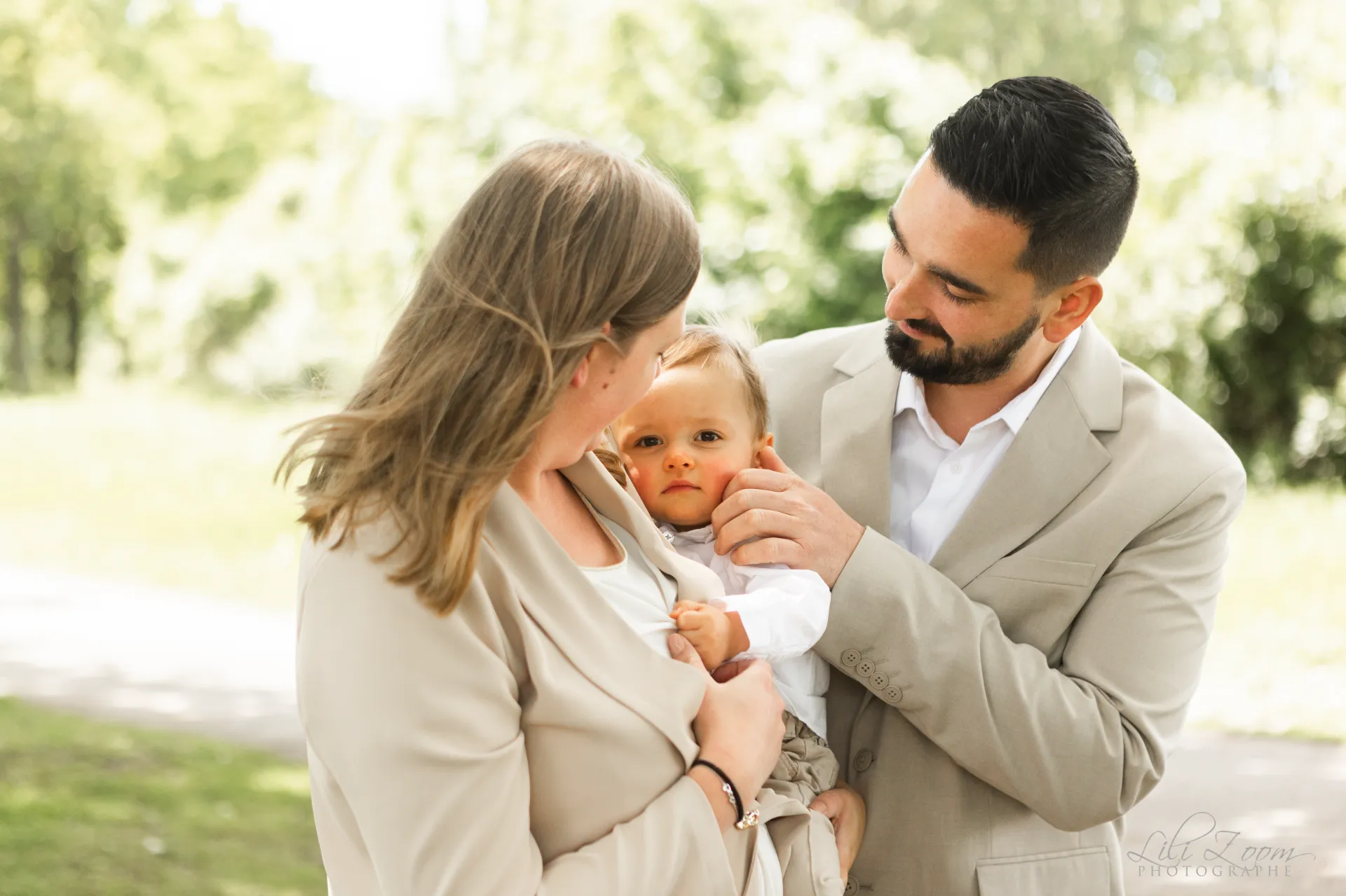 Parents élégants entourant leur petit garçon dans un parc verdoyant - Photographe famille Prairie de Caen