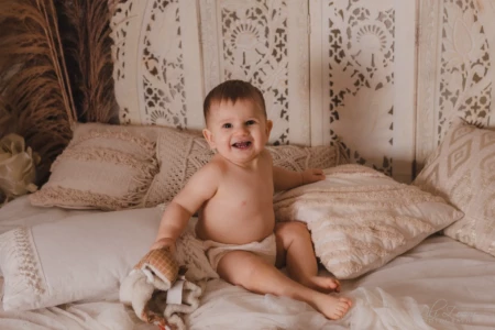 Bébé radieux et rieur assis parmi des coussins dans un décor bohème et naturel - Photographe Bébé au Studio à Giberville. Bébé radieux et rieur assis parmi des coussins dans un décor bohème et naturel - Photographe Bébé au Studio à Giberville.