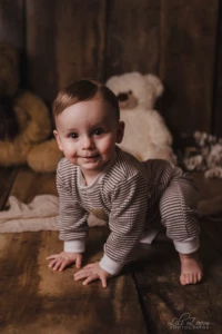 Portrait d'un bébé souriant à quatre pattes dans un décor boisé et chaleureux entouré de peluches - Photographe Bébé et Famille proche de Mondeville Portrait d'un bébé souriant à quatre pattes dans un décor boisé et chaleureux entouré de peluches - Photographe Bébé et Famille proche de Mondeville