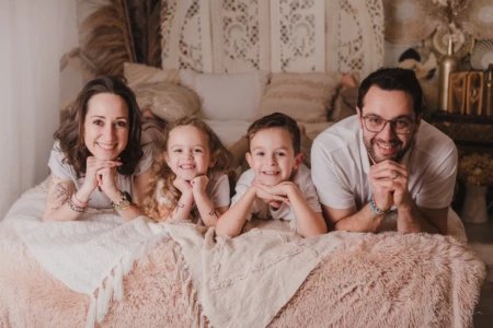 Portrait d'une famille rayonnante allongée sur un lit douillet dans un décor studio bohème et chaleureux - Photographe Famille secteur Mondeville Portrait d'une famille rayonnante allongée sur un lit douillet dans un décor studio bohème et chaleureux - Photographe Famille secteur Mondeville