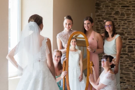 Mariée admirant son reflet dans un miroir tenu par ses demoiselles d'honneur complices - Photographe Famille à Giberville Mariée admirant son reflet dans un miroir tenu par ses demoiselles d'honneur complices - Photographe Famille à Giberville