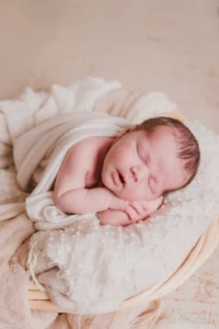 Nouveau-né paisiblement endormi dans un panier en osier aux tons crème et naturels - Photographe Naissance à Giberville Nouveau-né paisiblement endormi dans un panier en osier aux tons crème et naturels - Photographe Naissance à Giberville