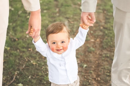 Bébé tenant la main de ses parents pour faire ses premiers pas dans l'herbe - Photographe enfant Suisse Normande Bébé tenant la main de ses parents pour faire ses premiers pas dans l'herbe - Photographe enfant Suisse Normande