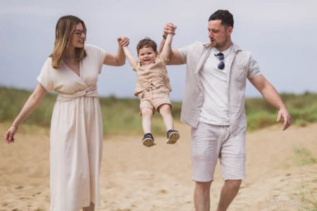 Parents souriants soulevant leur petit garçon par les mains sur la plage - Photographe famille Houlgate Parents souriants soulevant leur petit garçon par les mains sur la plage - Photographe famille Houlgate