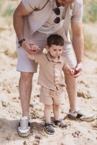 Père tenant la main de son jeune fils marchant dans le sable - Photographe enfant Deauville Père tenant la main de son jeune fils marchant dans le sable - Photographe enfant Deauville