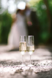 Deux flûtes de champagne posées sur le sol avec des mariés flous en arrière-plan - Photographe mariage Suisse Normande Deux flûtes de champagne posées sur le sol avec des mariés flous en arrière-plan - Photographe mariage Suisse Normande