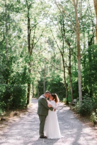 Couple de mariés se tenant par les épaules dans une allée boisée ensoleillée - Photographe mariage Caen Couple de mariés se tenant par les épaules dans une allée boisée ensoleillée - Photographe mariage Caen