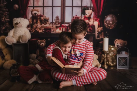 Deux enfants lisent un livre dans un décor rempli de peluches et de cadeaux. Deux enfants assis sur le sol lisent ensemble un livre, entourés de peluches, de cadeaux et de décorations festives.